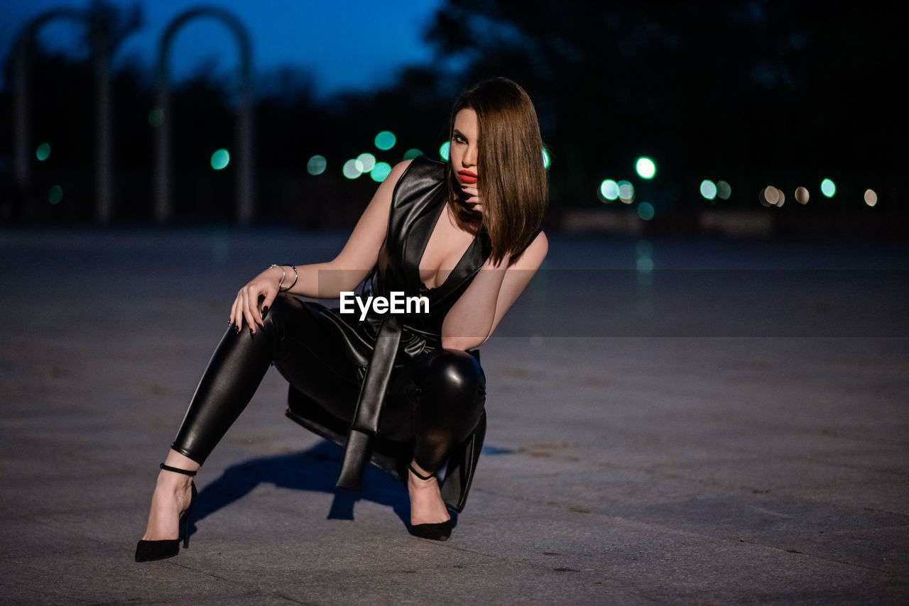 Woman sitting in city at night