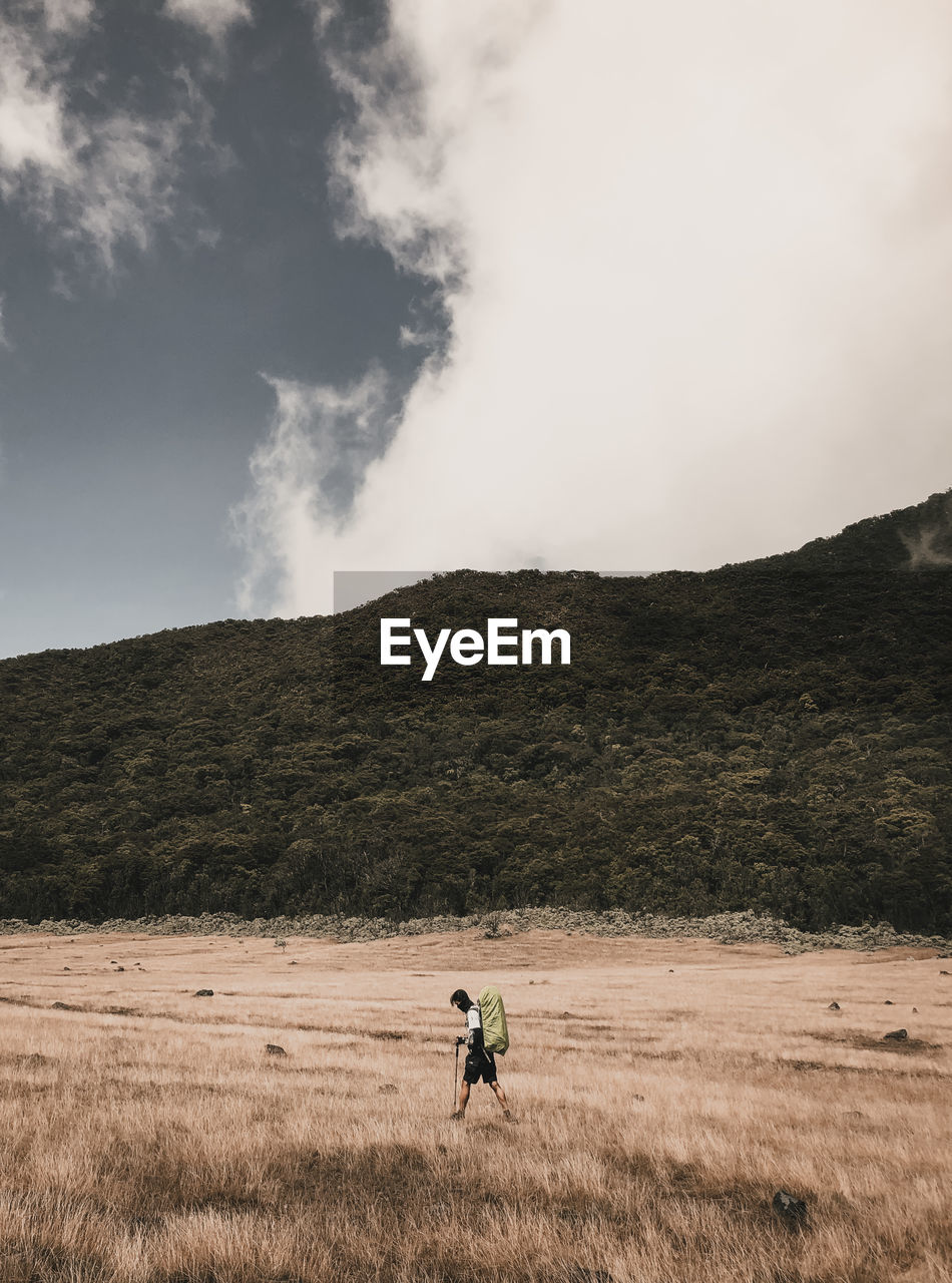 Man riding on field against sky