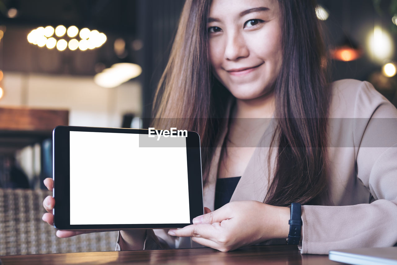 Portrait of businesswoman holding digital tablet at cafe