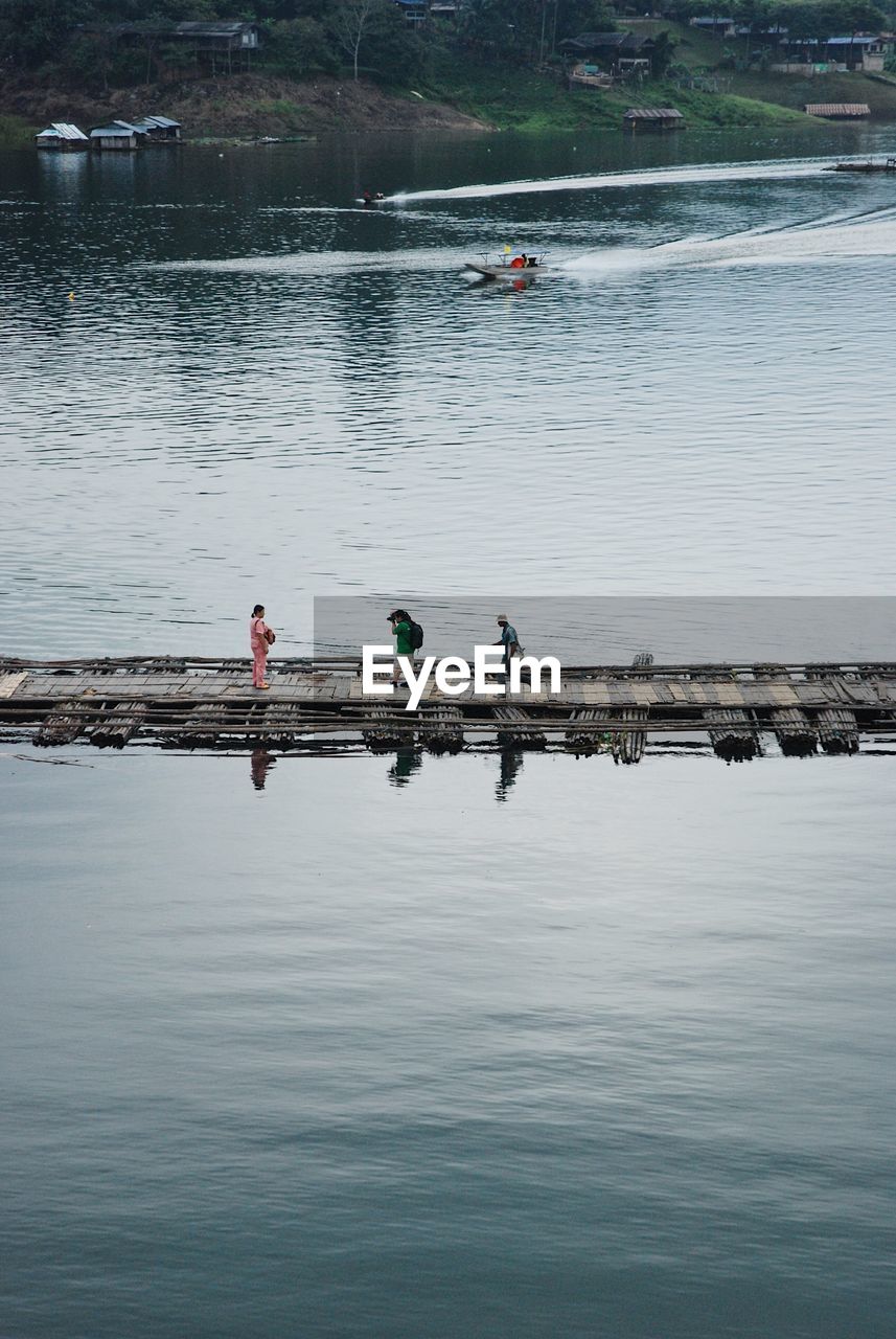 Man photographing woman while standing on pier