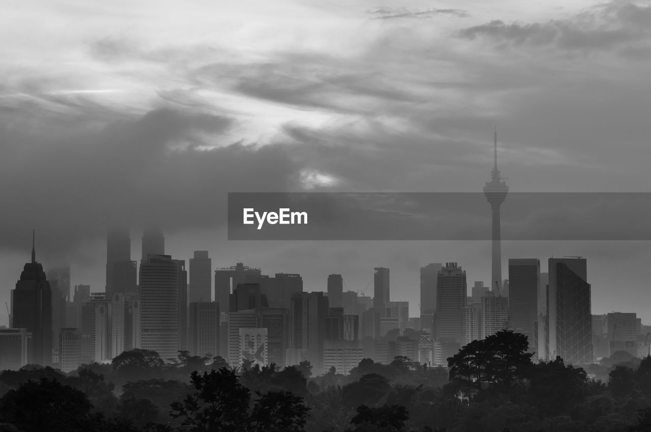 Buildings in city against cloudy sky