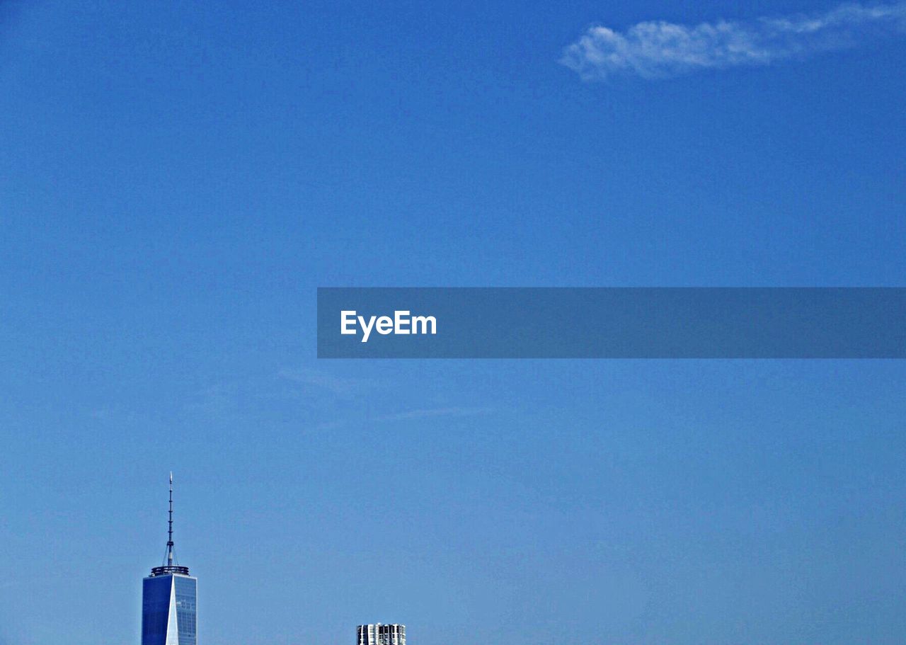 High section of skyscraper with spire against blue sky