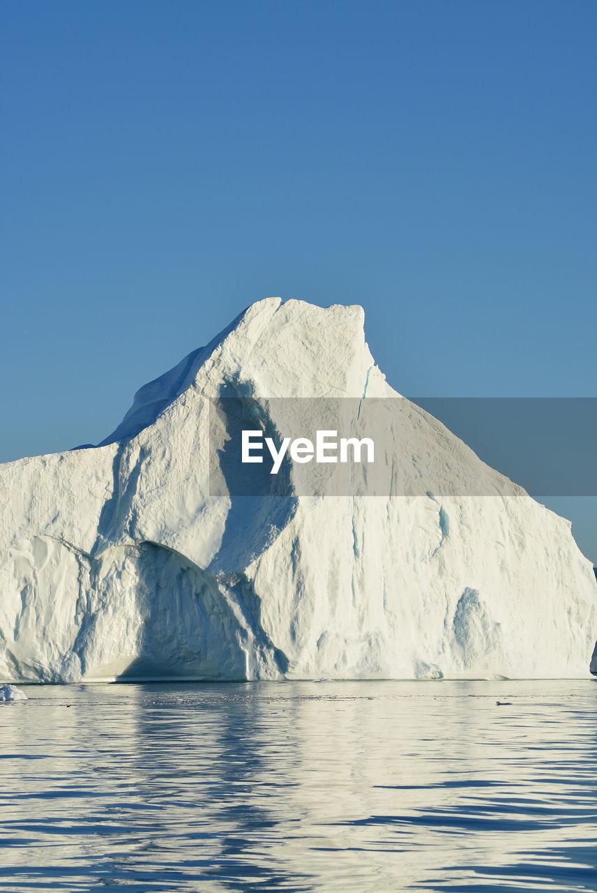 View of majestic iceberg in sea against sky