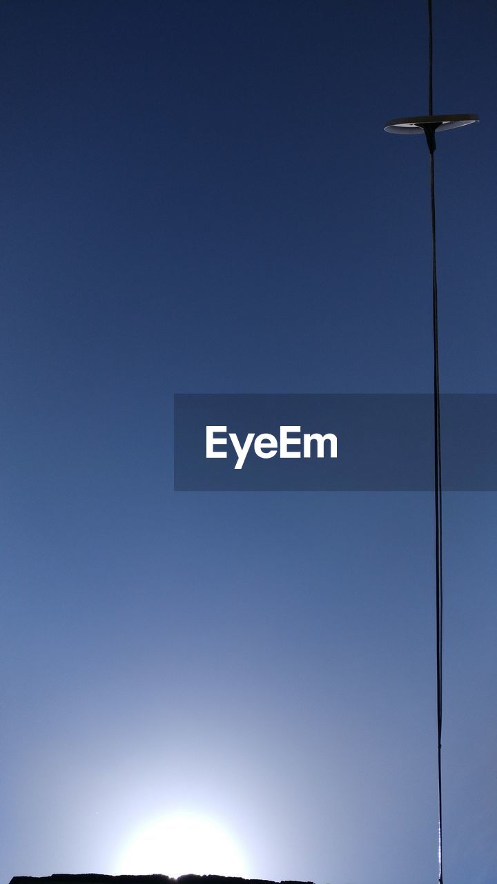 LOW ANGLE VIEW OF WIND TURBINES AGAINST CLEAR BLUE SKY