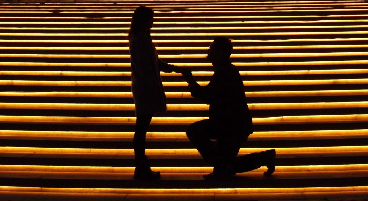 Silhouette man on knee holding woman hand at night