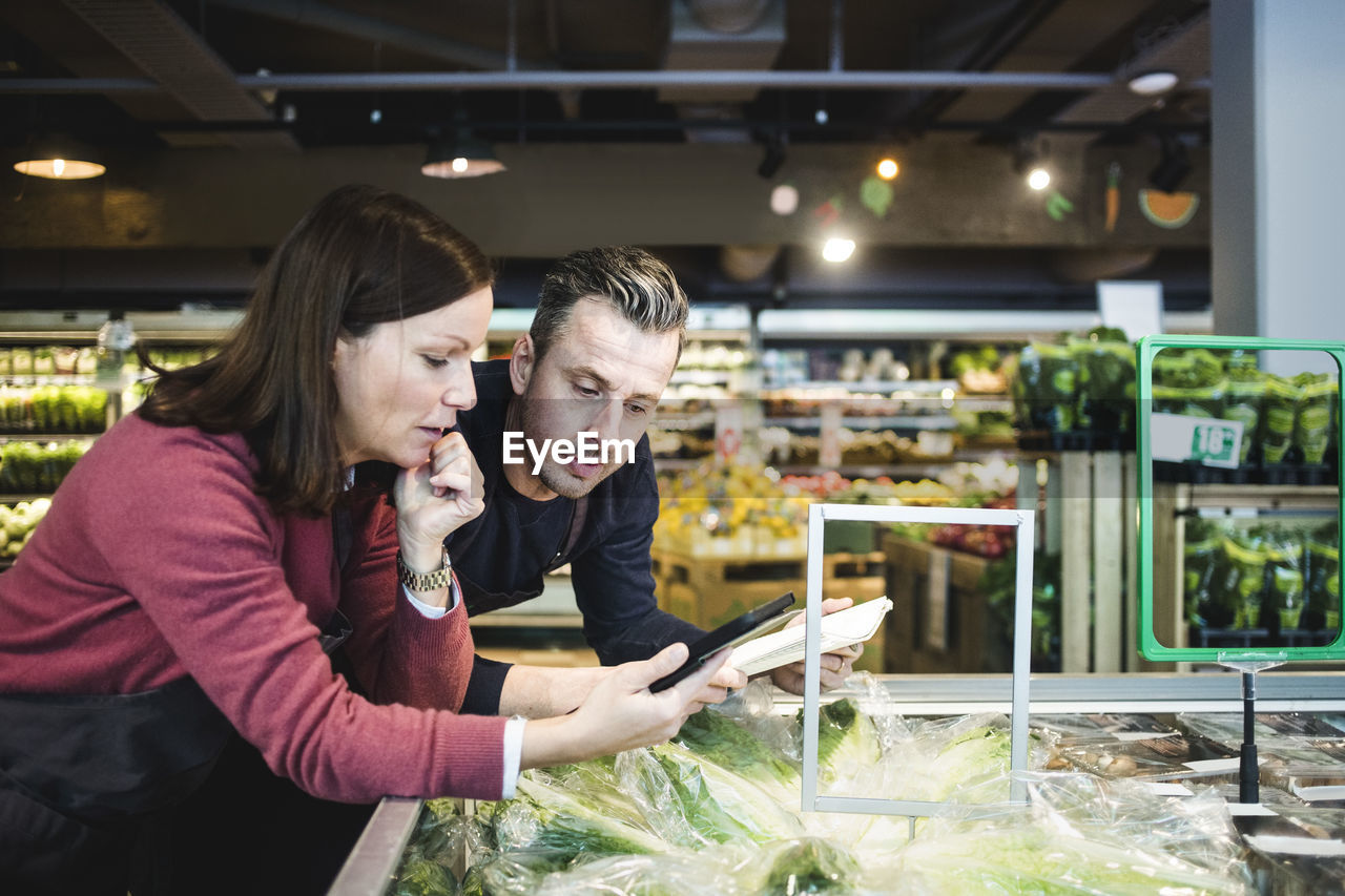 Sales clerks using digital tablet at market stall in supermarket