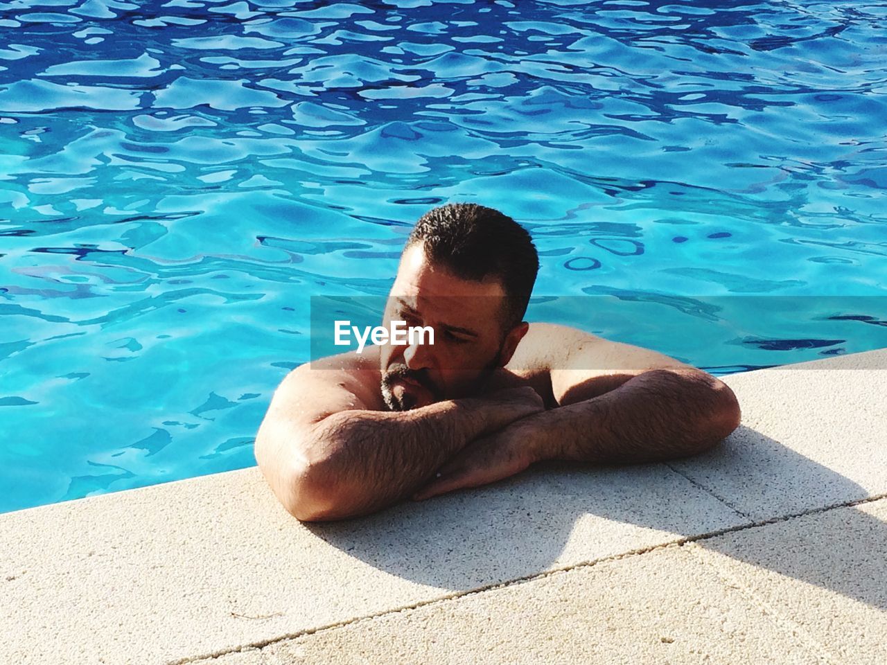 Thoughtful mature man relaxing in swimming pool