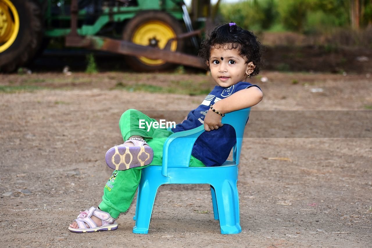 Side view of cute girl looking away while sitting on chair