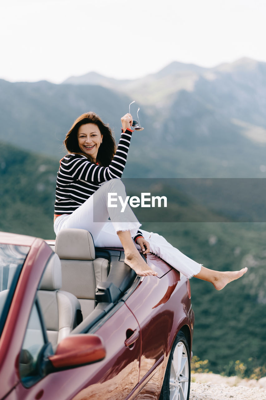 WOMAN SITTING WITH UMBRELLA ON MOUNTAIN