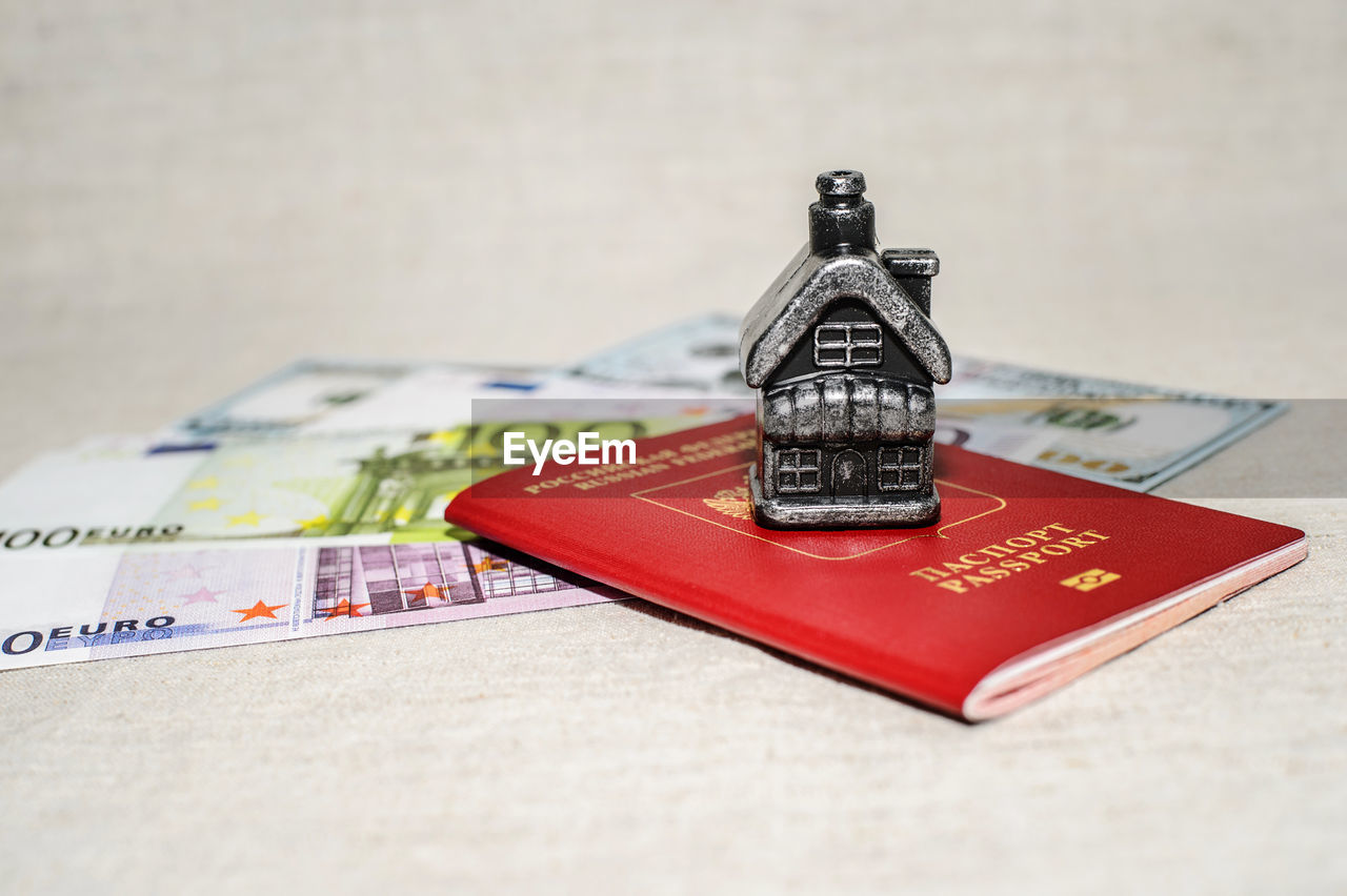 Close-up of money with passport and model home on table