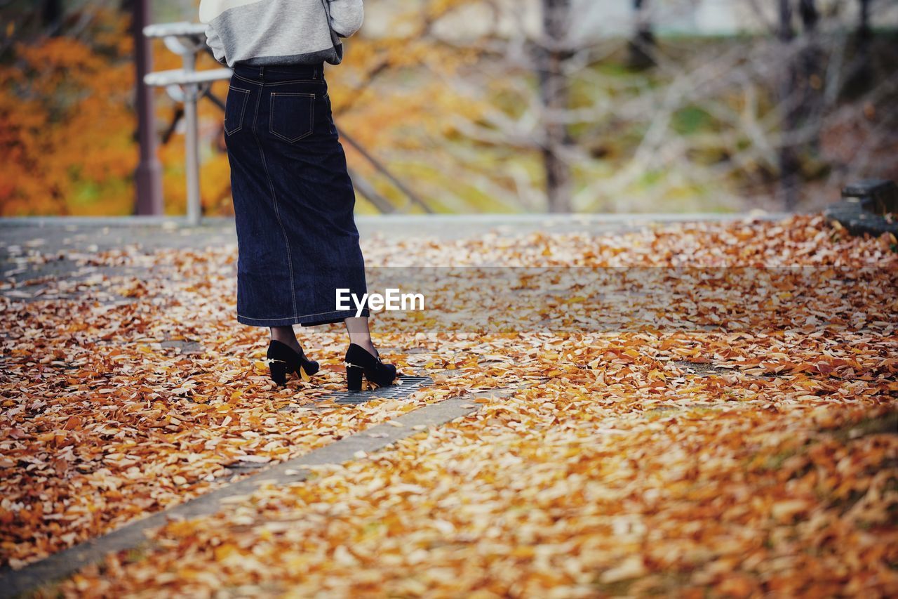 Low section of woman standing on street during autumn