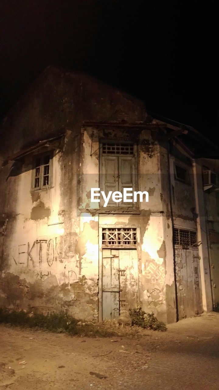 architecture, built structure, darkness, night, light, building exterior, abandoned, no people, building, house, illuminated, old, communication, entrance, text, ancient history, spooky, history, damaged, sign, western script, rundown, door, outdoors, nature, the past