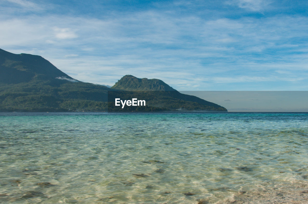 SCENIC VIEW OF SEA BY MOUNTAINS AGAINST SKY