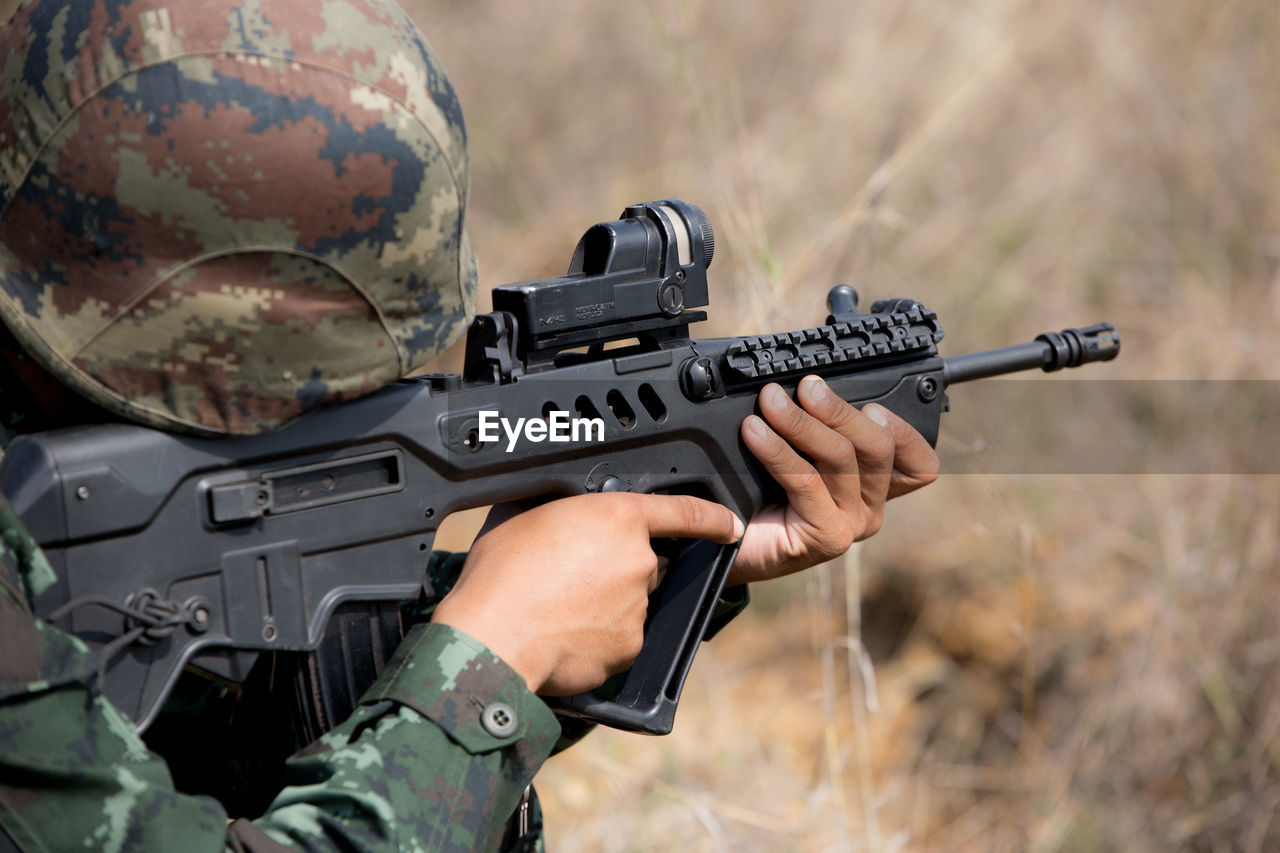 Close-up of army soldier aiming with rifle