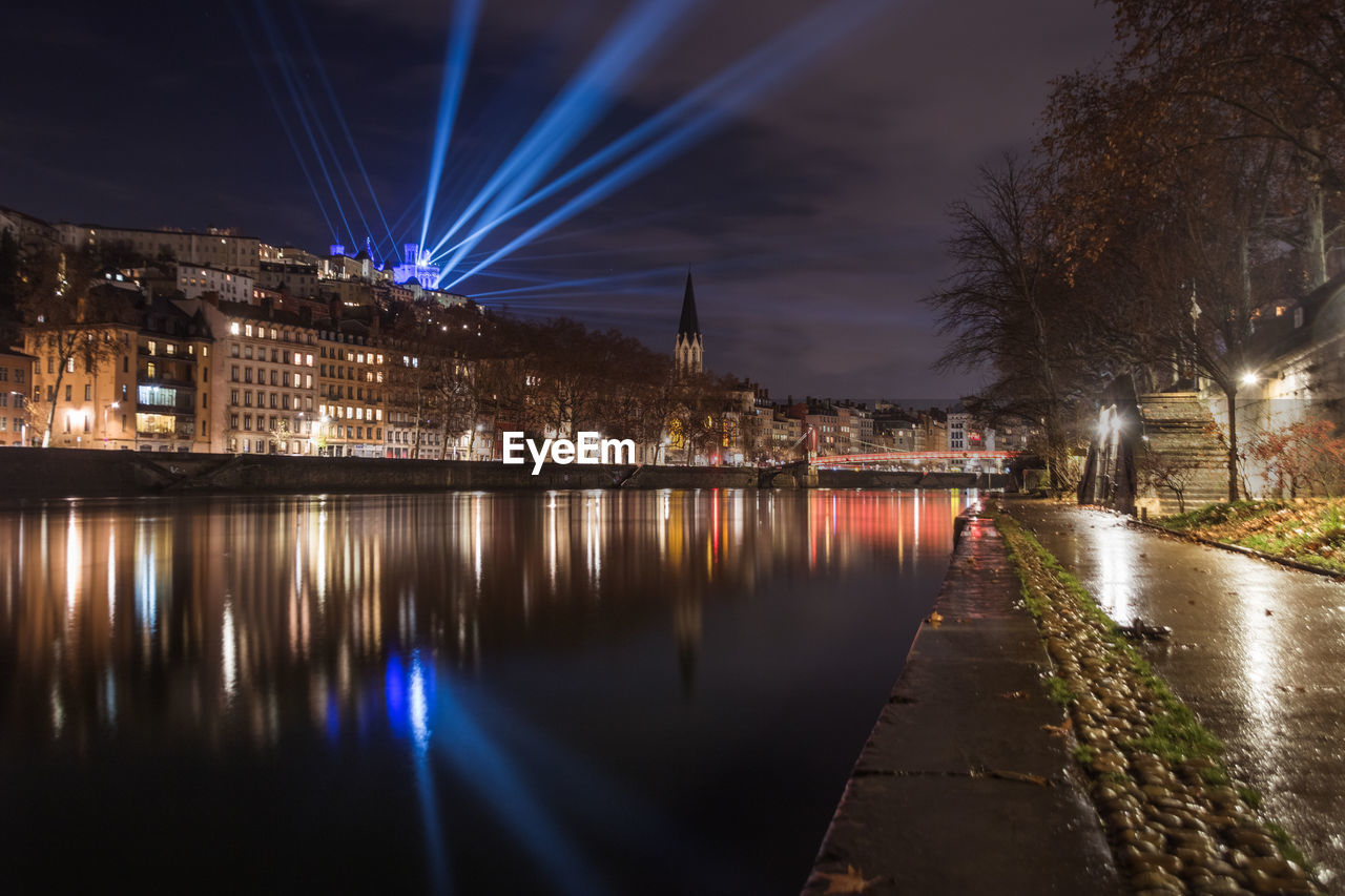 illuminated bridge over river in city at night