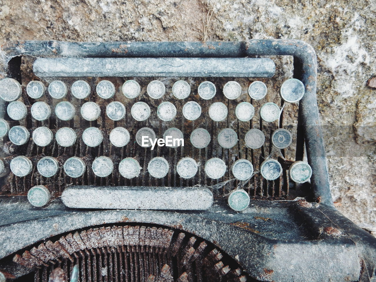 Close-up of abandoned typewriter by wall
