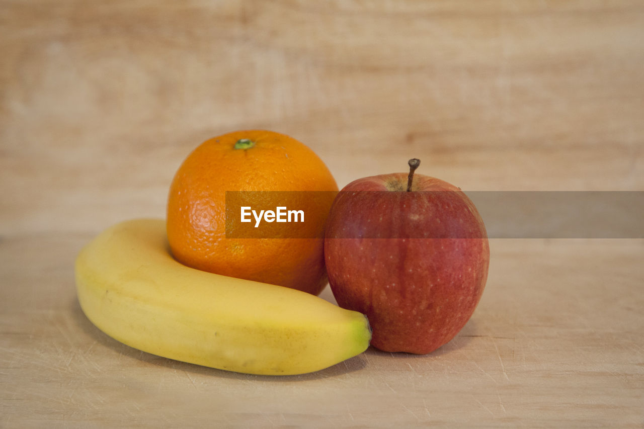 CLOSE-UP OF APPLES IN ORANGE ON TABLE