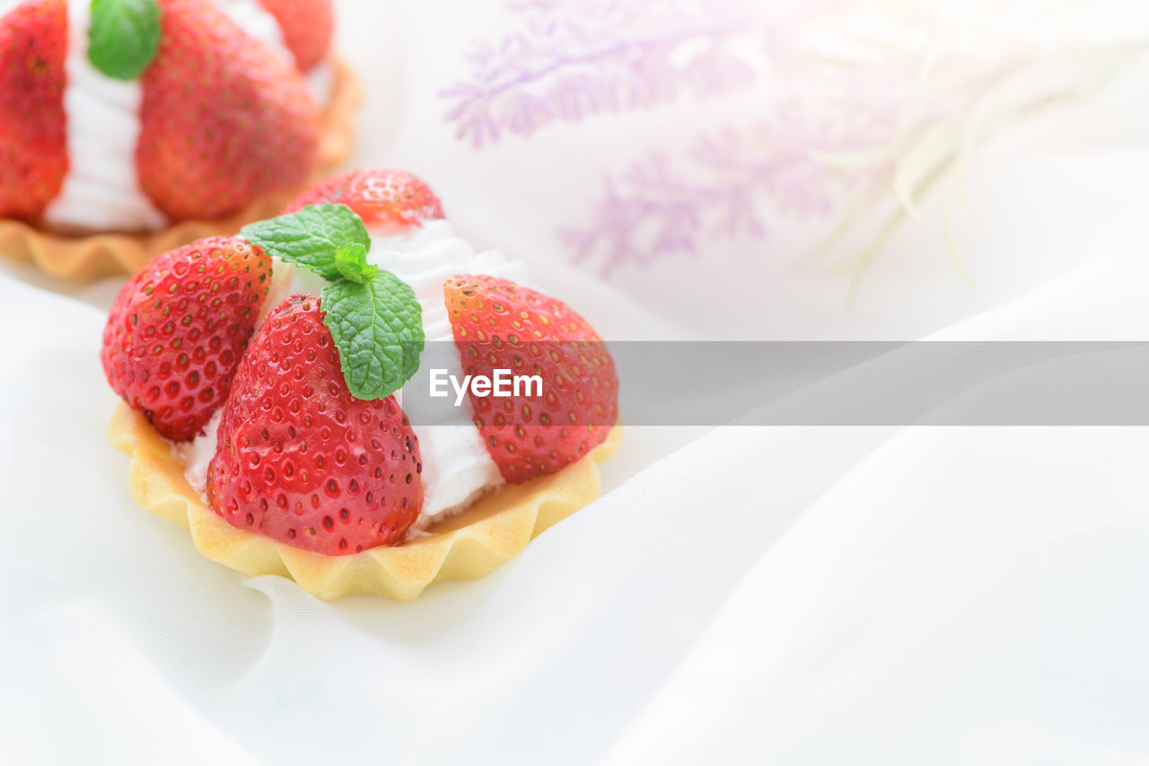 Strawberry tart with mint leaf on cream cheese on white cloth background, minimal cake and bakery
