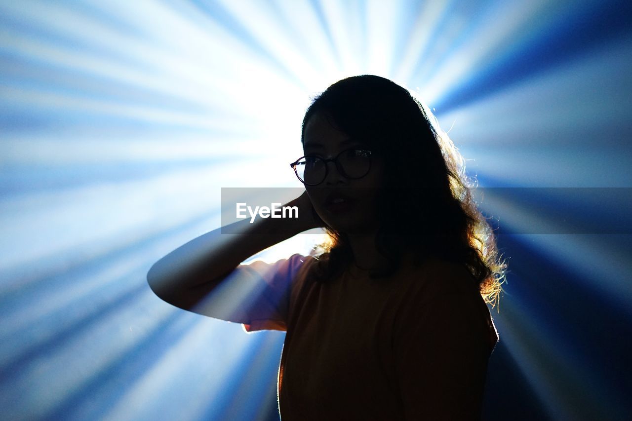 Young woman standing against light beams