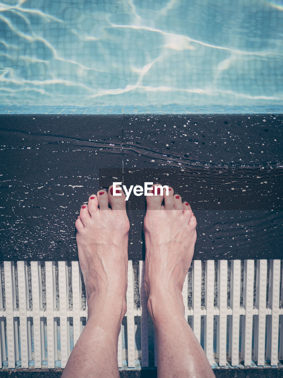 Low section of woman standing by swimming pool