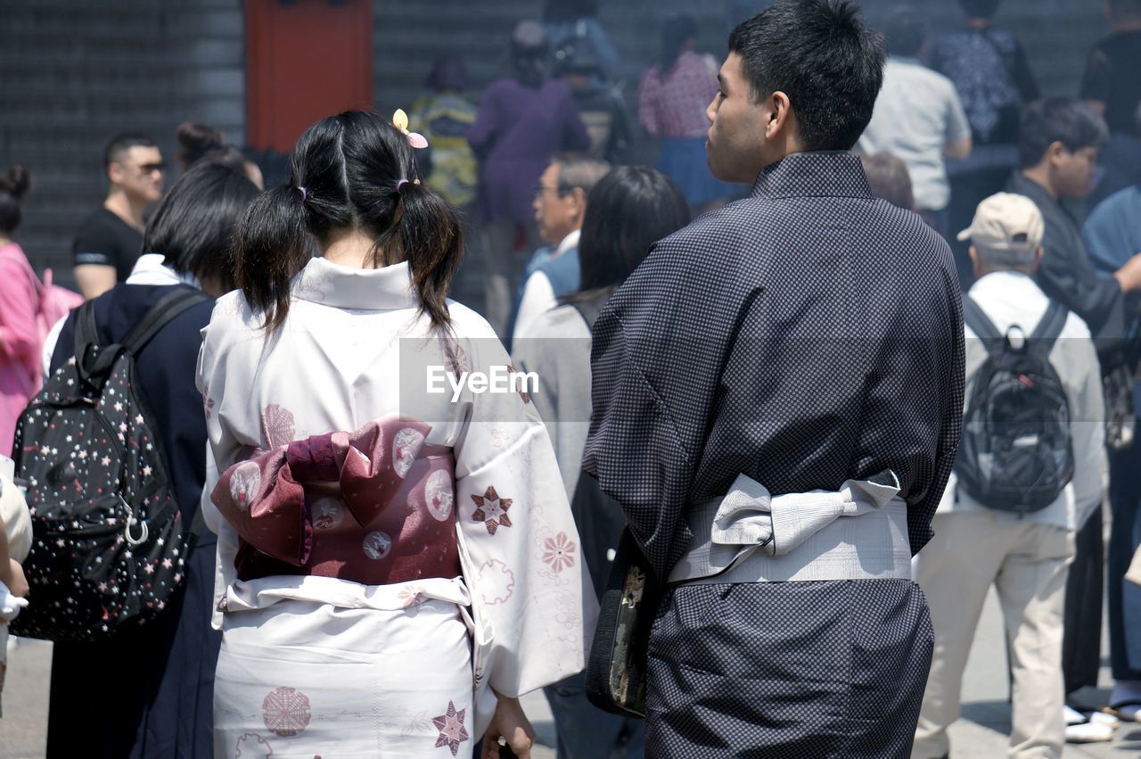 REAR VIEW OF PEOPLE ON STREET IN CITY