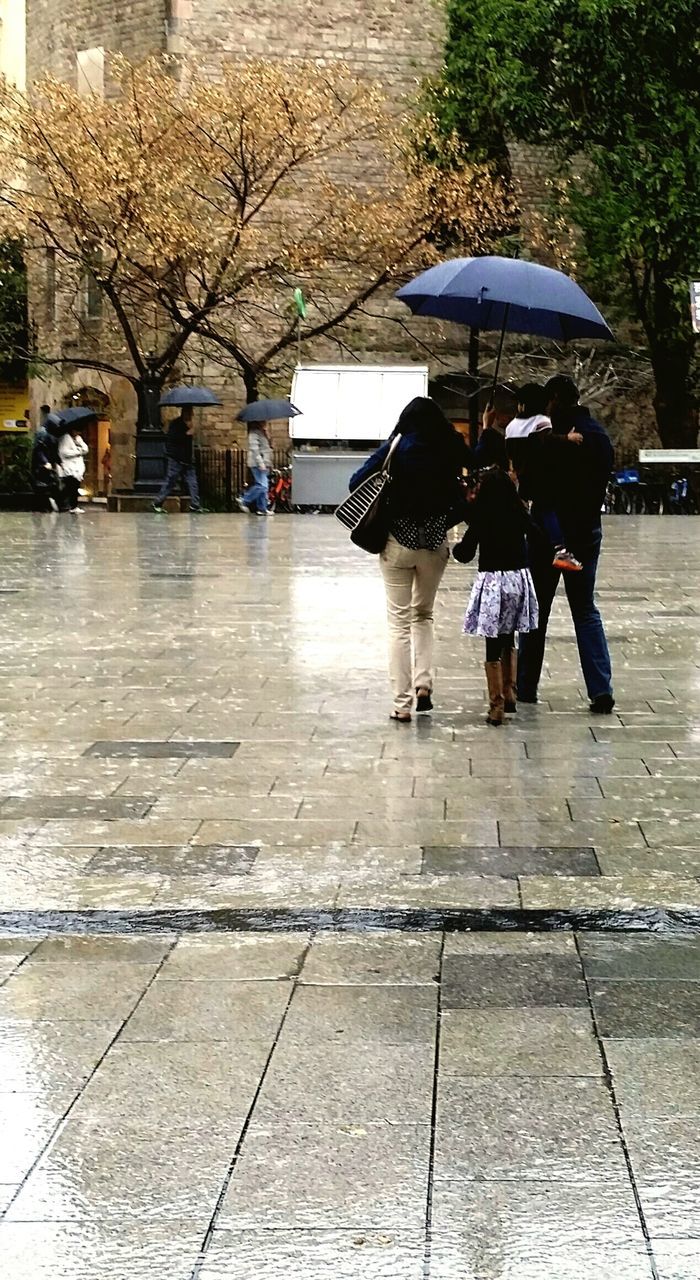 REAR VIEW OF WOMAN WITH UMBRELLA WALKING ON STREET