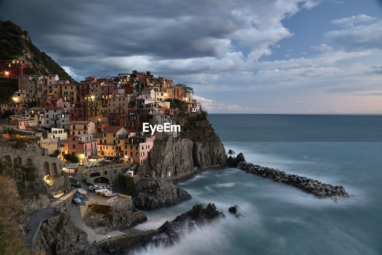 Panoramic view of rough sea and manarola buildings against sky in cinqueterre