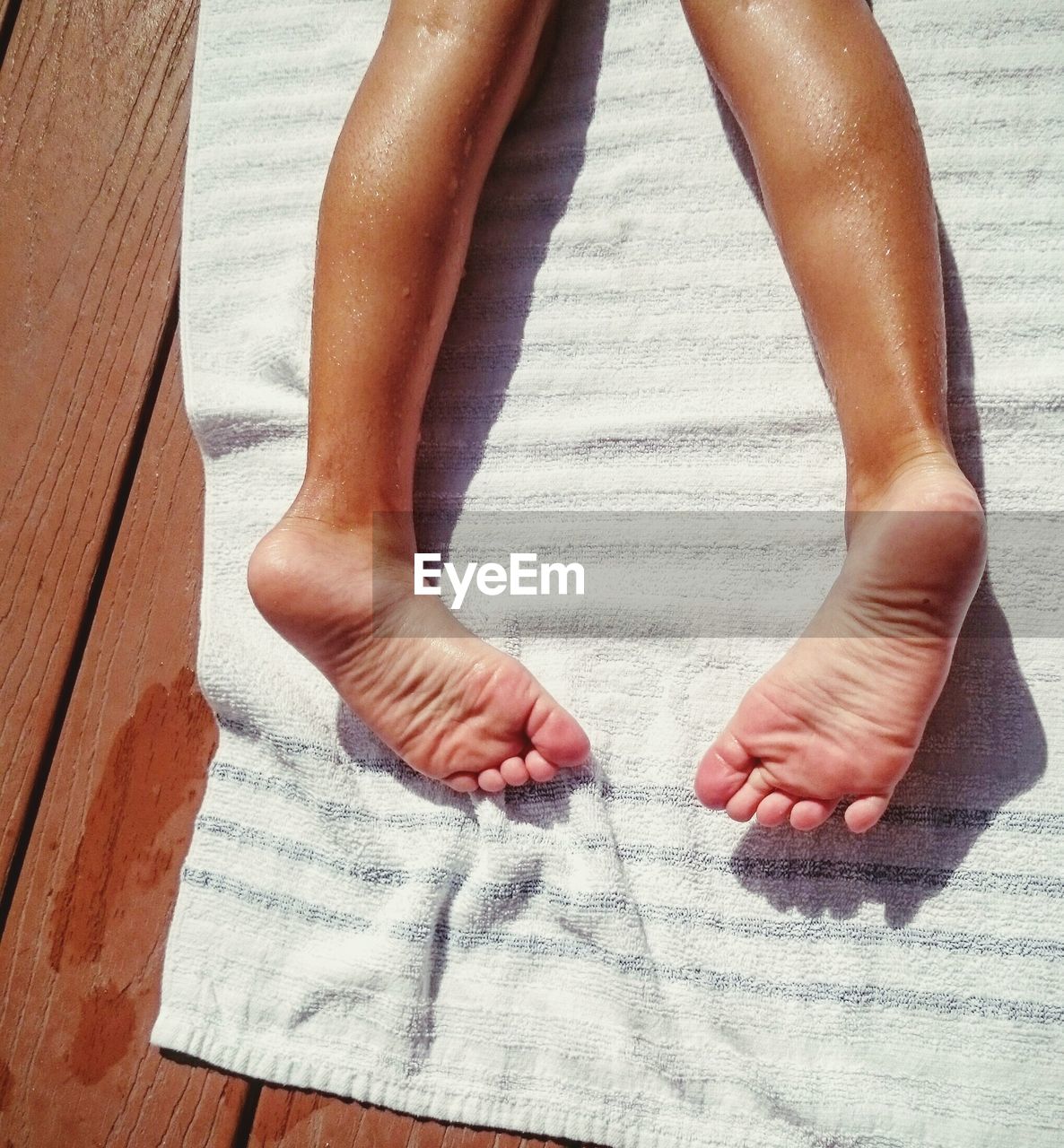 Low section of kid lying on towel at poolside