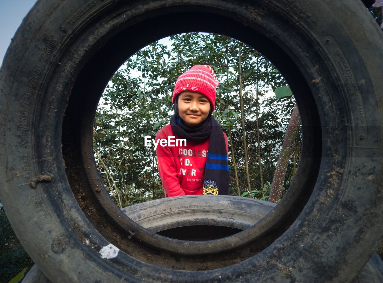 Portrait of smiling girl seen through tire