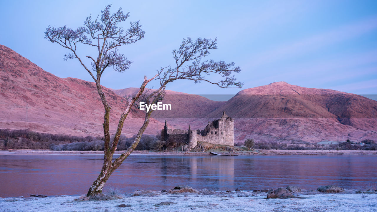 Sunrise on frosty winter morning with reflections of kilchurn castle in loch awe, highlands scotland