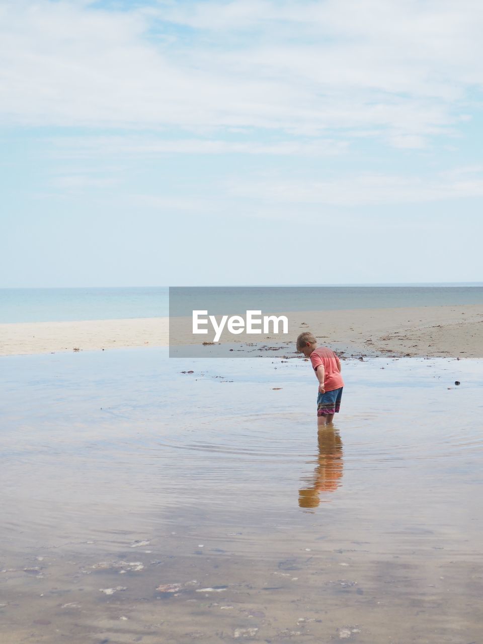 Boy standing on beach against sky