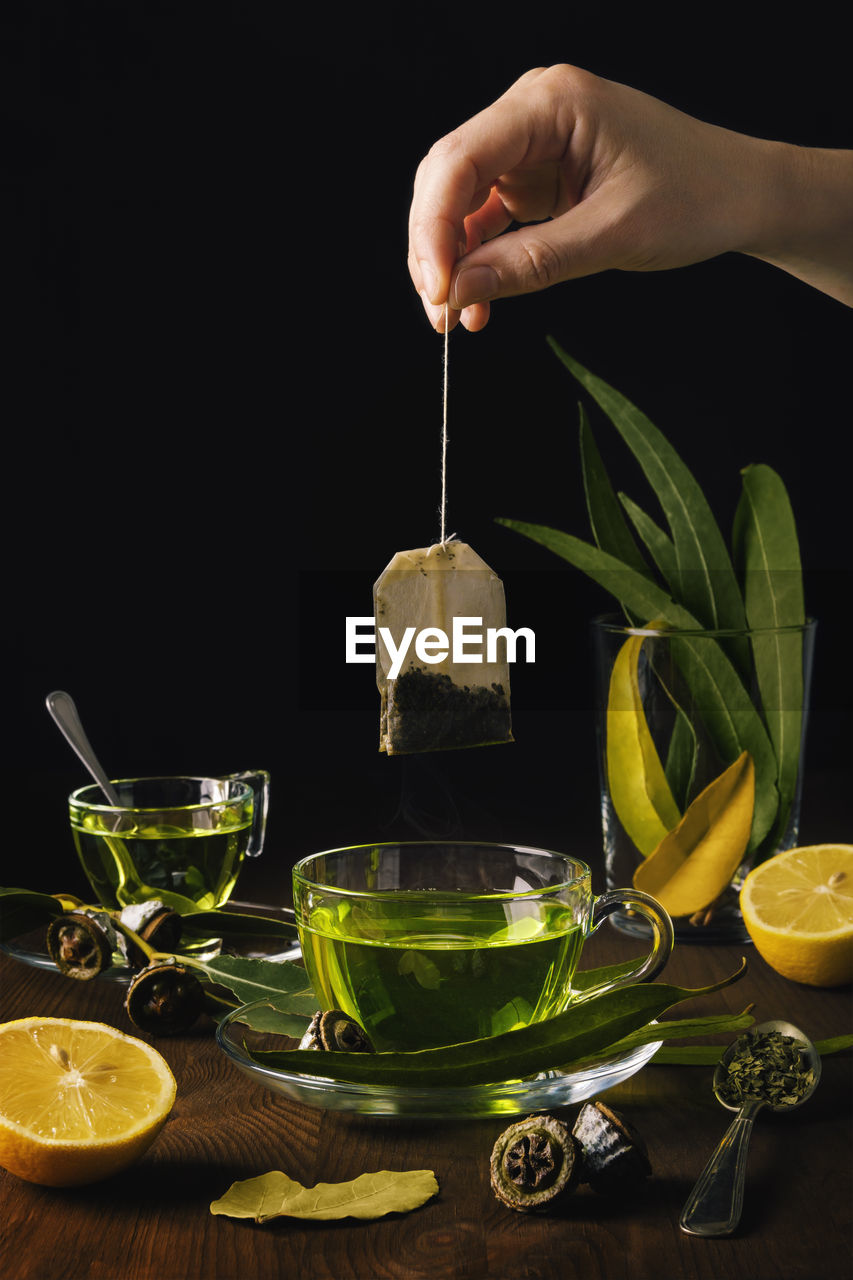 Person puts a bag of herbs in a cup of tea with eucalyptus and lemons