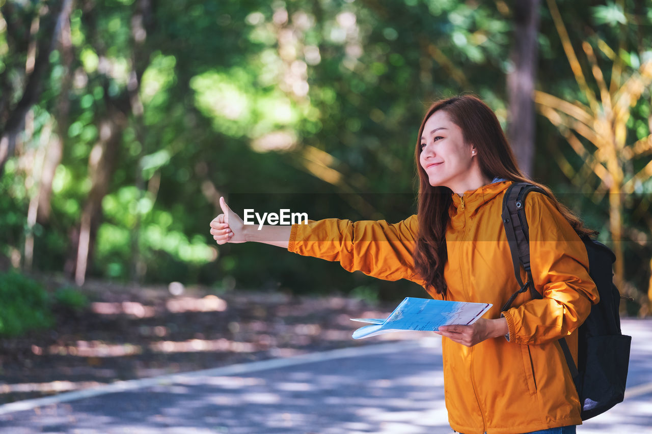 Portrait of young woman standing against trees