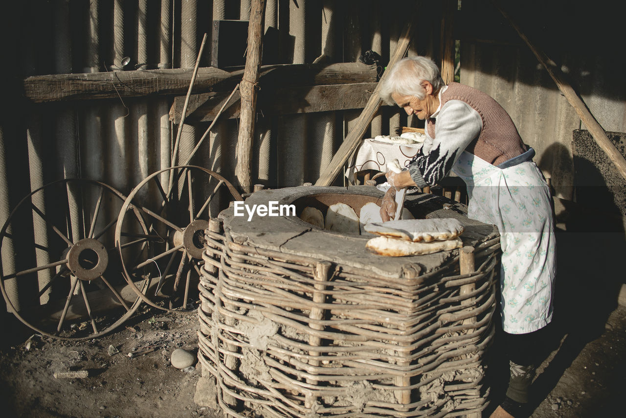 MIDSECTION OF MAN WORKING IN WICKER BASKET