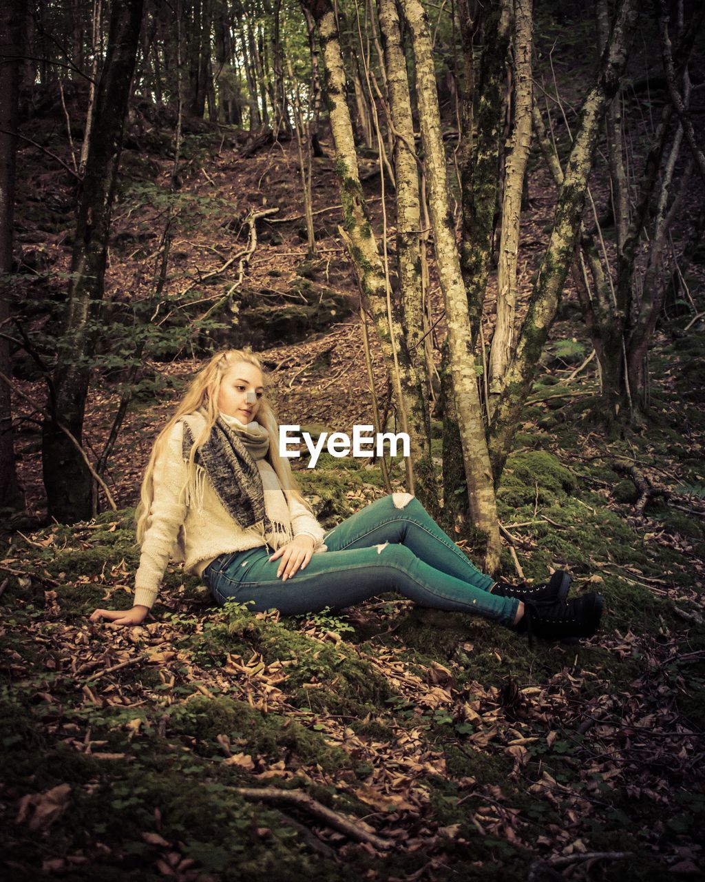 YOUNG WOMAN SITTING ON TREE IN FOREST