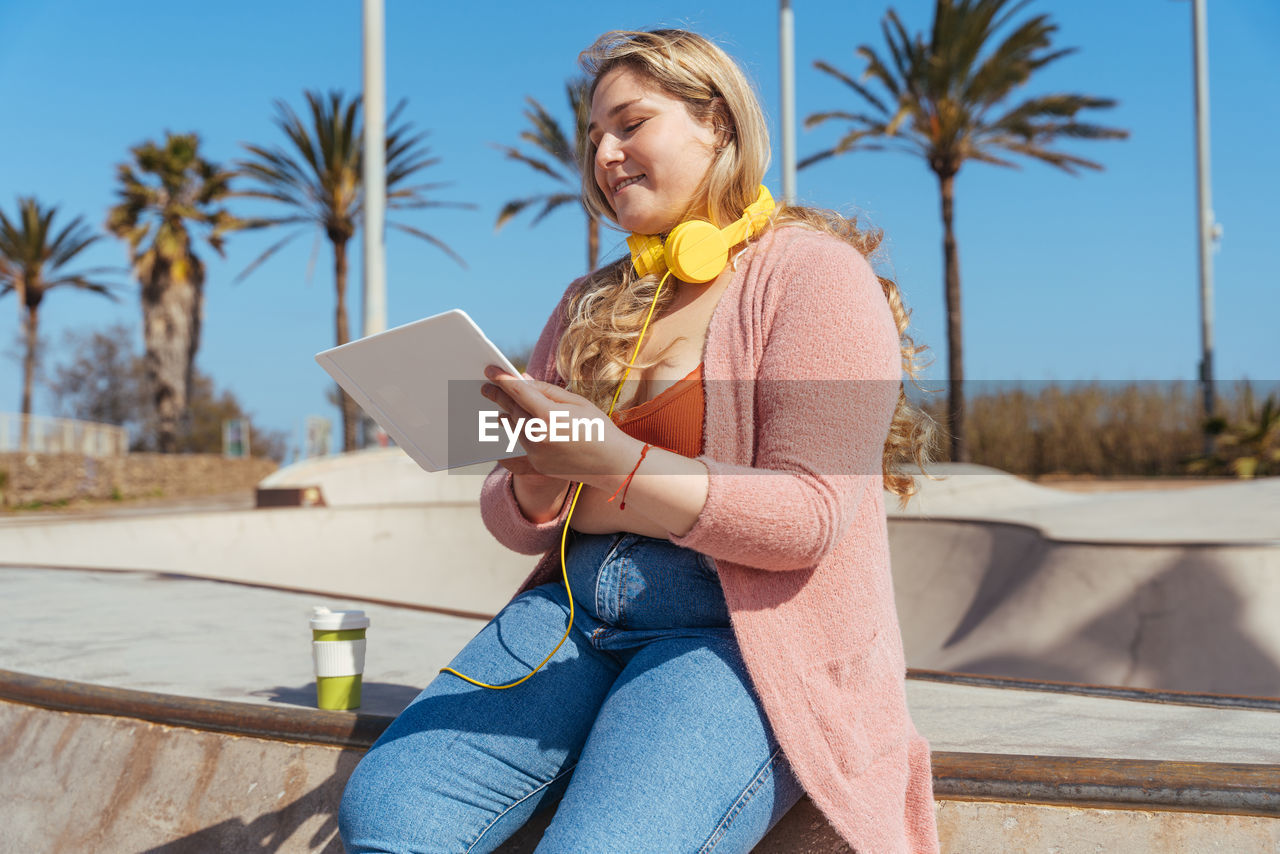 Chubby girl using digital tablet sitting outdoors