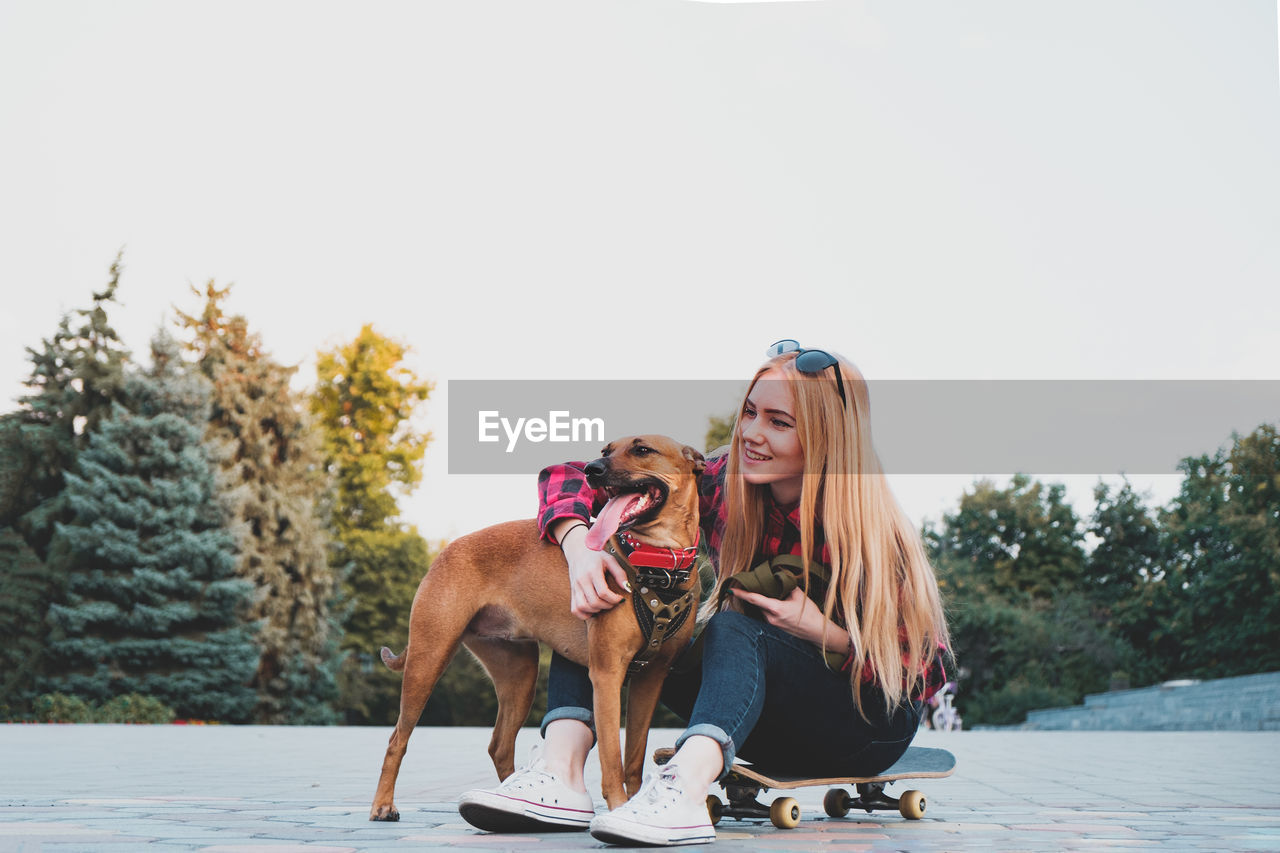 YOUNG WOMAN WITH DOG ON THE BEACH