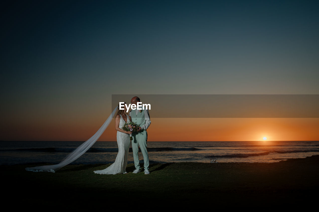 Man standing on beach against sky during sunset