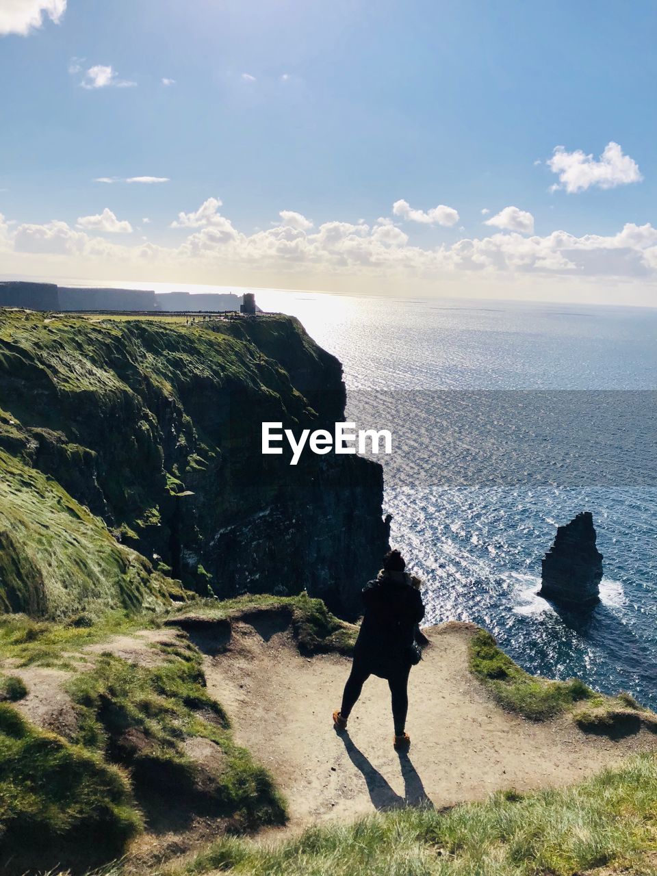 Full length of woman standing on mountain by sea against sky