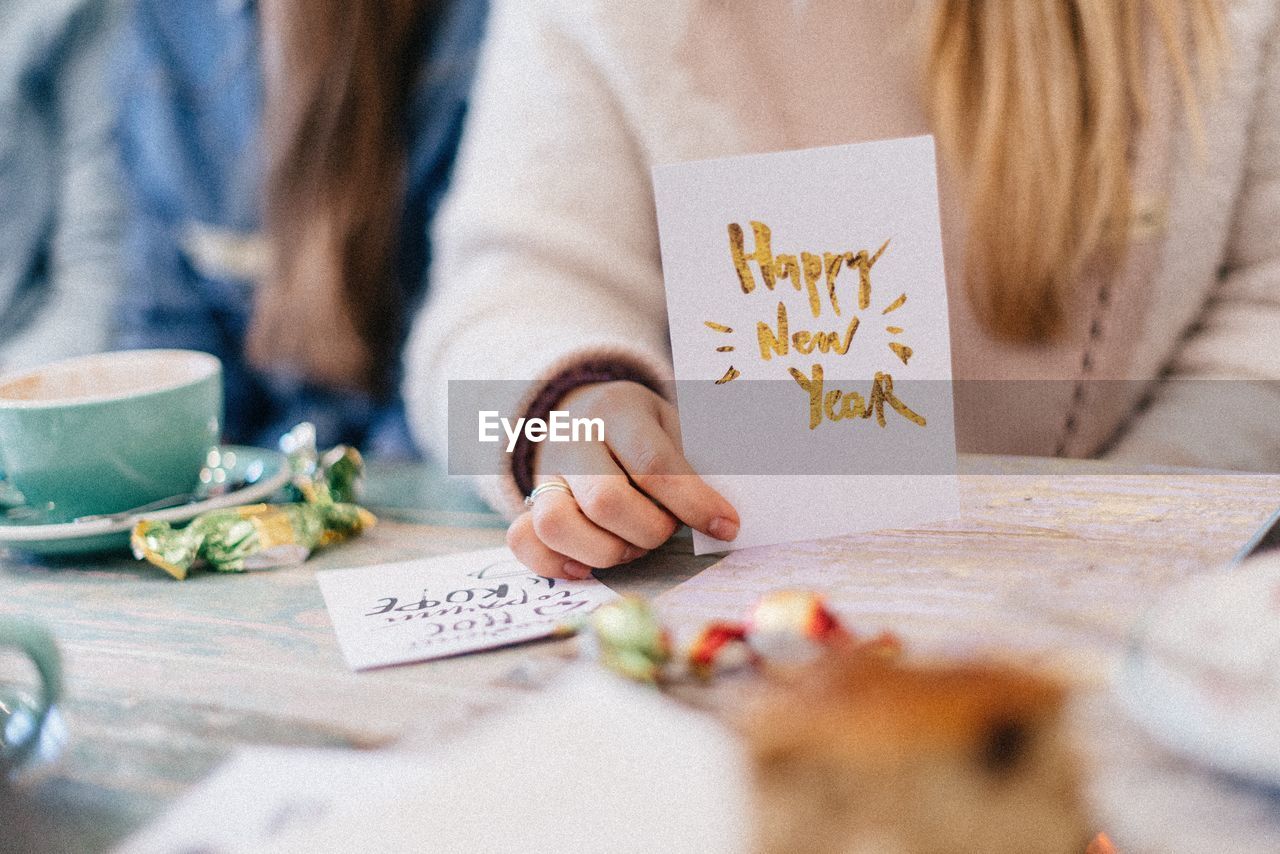 Midsection of girl holding new year card at table