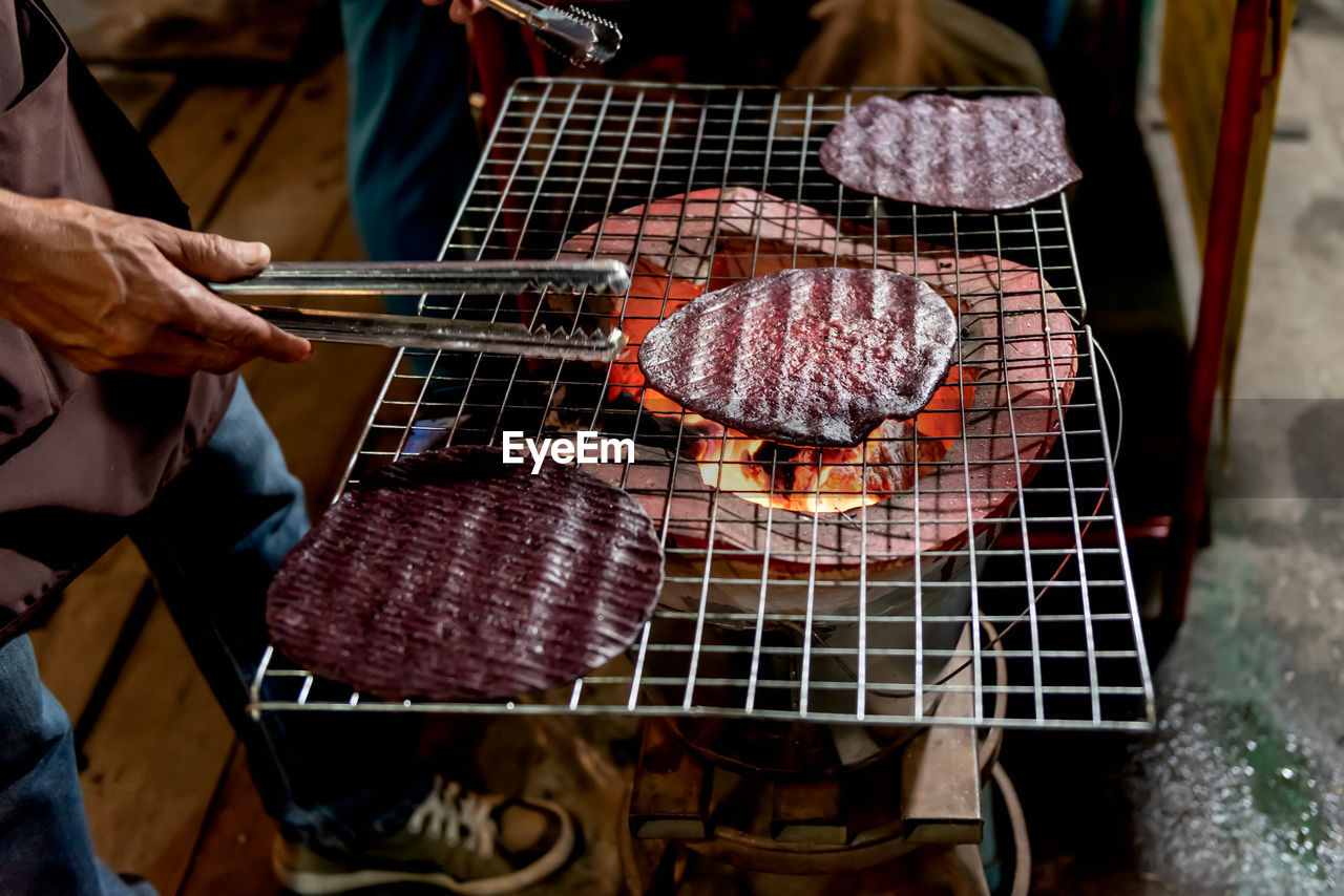 MIDSECTION OF MAN PREPARING BARBECUE GRILL