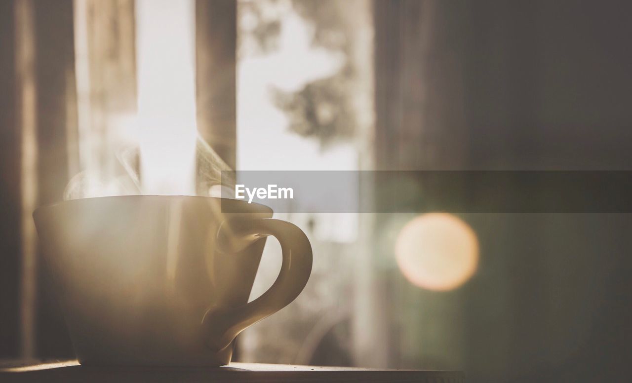 Close-up of coffee cup on table against window