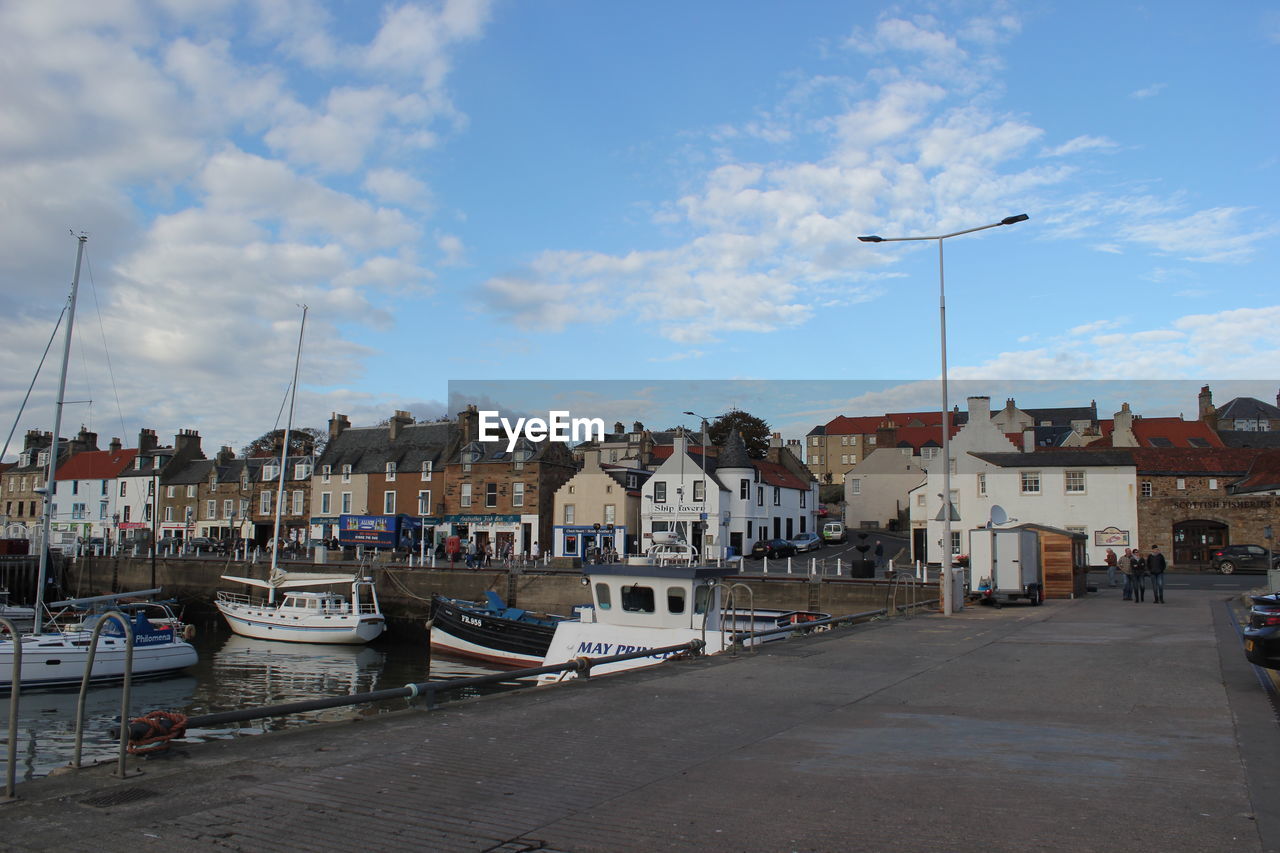 Boats moored at harbor against sky