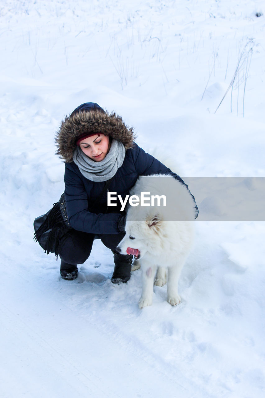 Full length of woman with dog on snow field