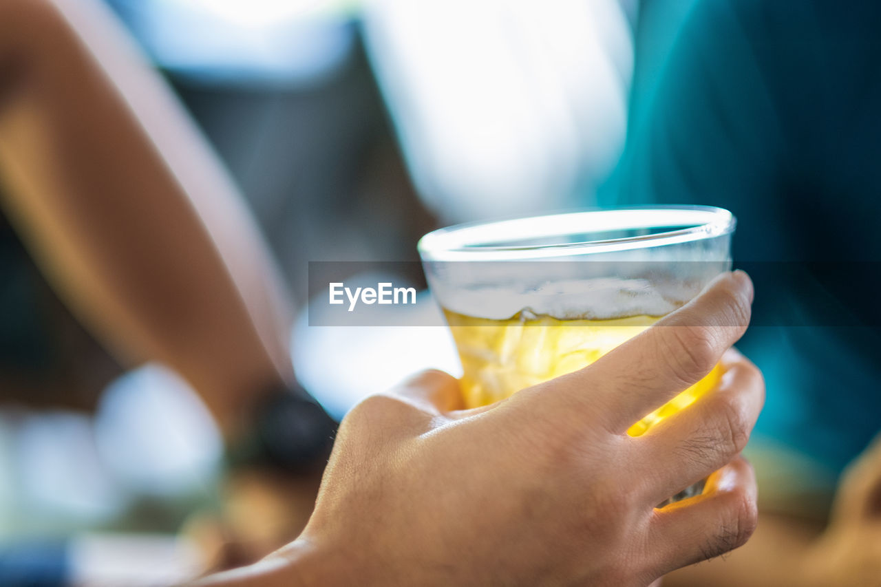 Close-up of hand holding beer glass