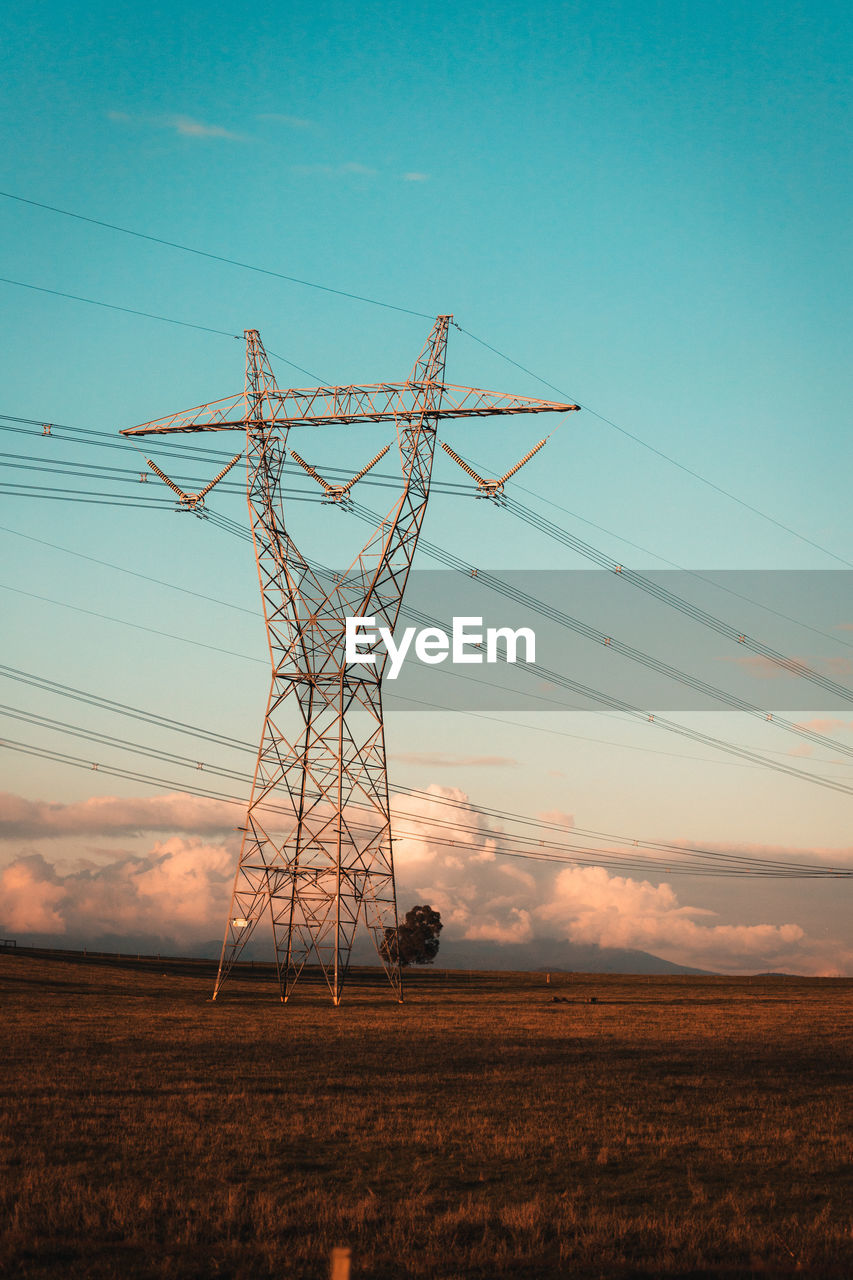 Low angle view of electricity pylon on field against sky