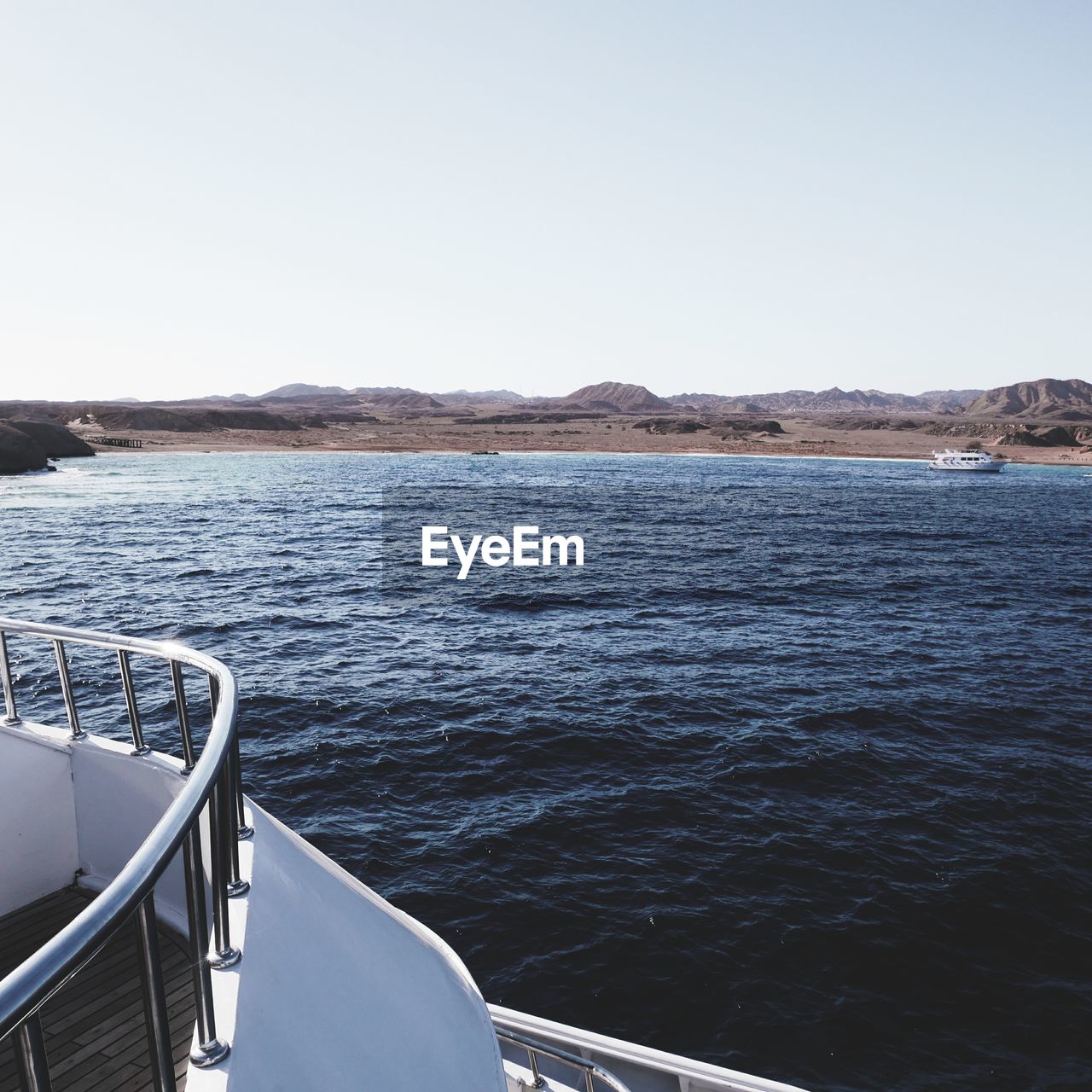 SCENIC VIEW OF SEA BY MOUNTAIN AGAINST CLEAR SKY