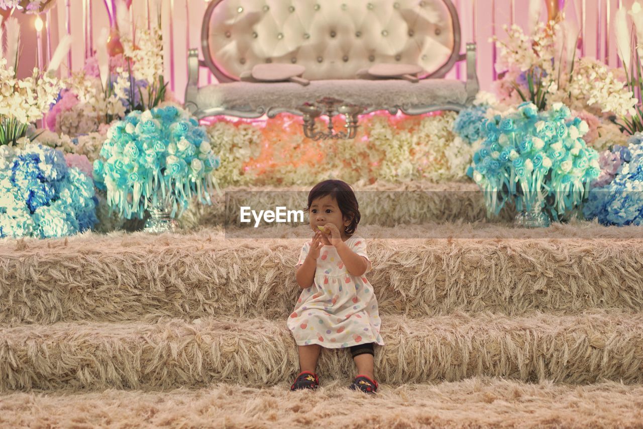 Full length of cute baby girl looking away while sitting on steps against decorations