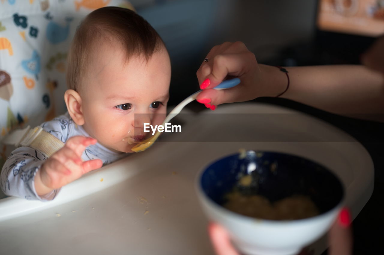 Woman's hand feeding her baby son with spoon