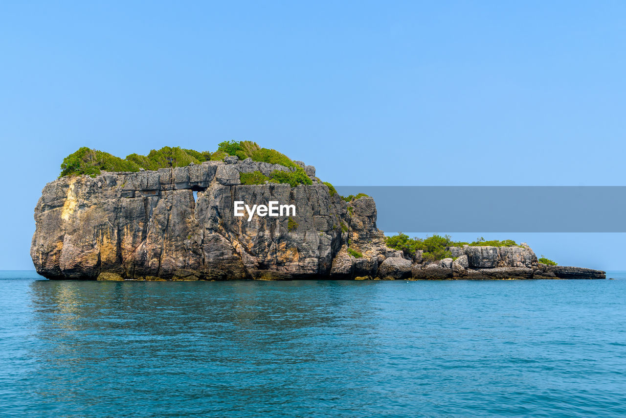 ROCK FORMATION IN SEA AGAINST CLEAR SKY